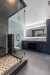 Master Bathroom - Contemporary master bathroom gray tile gray floor and concrete wall, split-pebble shower floor, steam spa bathroom idea with overlay-panel gray cabinets, porcelain white countertop,