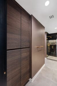 This image features a sleek, modern toilet set against a backdrop of warm, wood-paneled walls, showcasing the expert craftsmanship of StyleCraft Cabinets in a Texas master bathroom. The clean lines and warm tones of the wood panels offer a serene and refined aesthetic, while the smart toilet boasts advanced features for comfort and hygiene, reflecting the innovation and luxury of modern bathroom design.